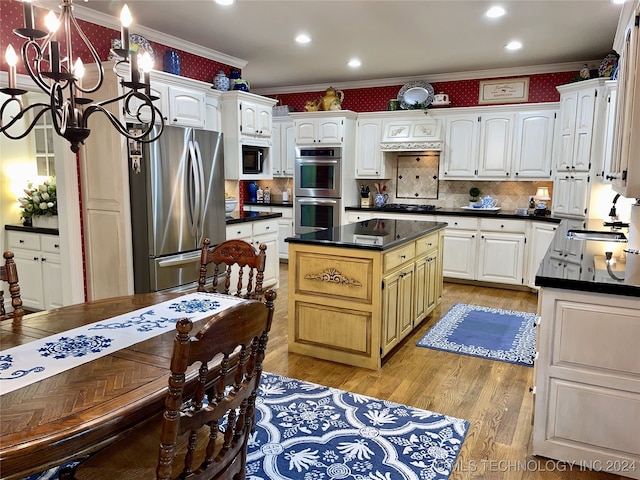 kitchen with light hardwood / wood-style floors, white cabinetry, appliances with stainless steel finishes, ornamental molding, and a center island