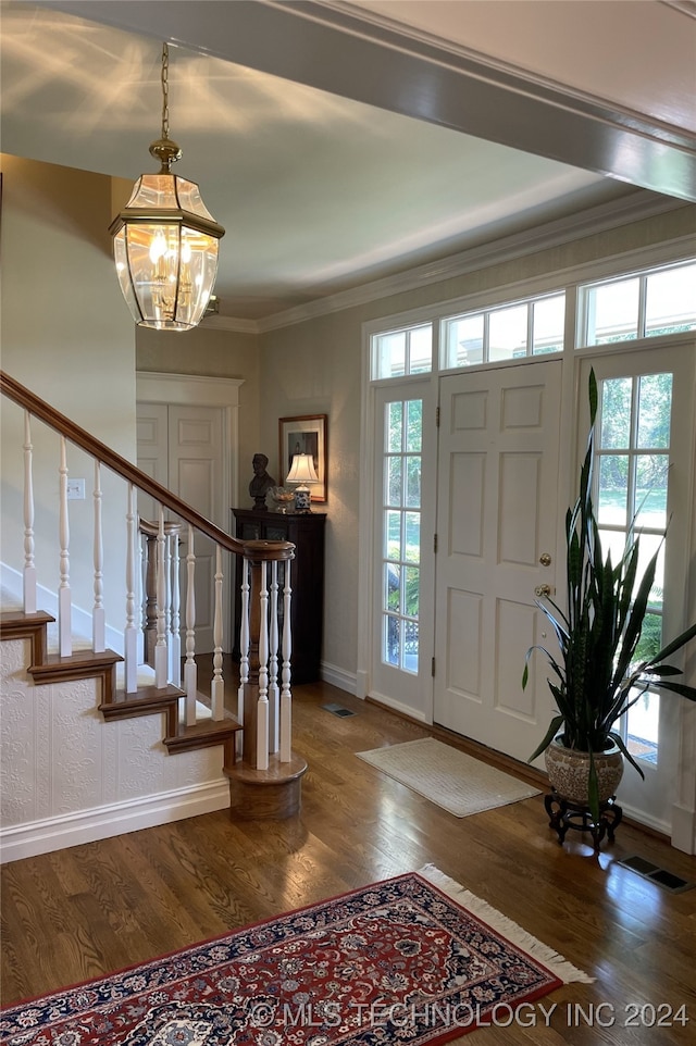 entrance foyer featuring hardwood / wood-style floors, a notable chandelier, and crown molding