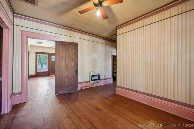 spare room featuring dark hardwood / wood-style floors, ceiling fan, and heating unit