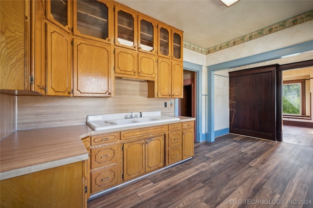 kitchen with dark hardwood / wood-style flooring, a barn door, sink, and backsplash