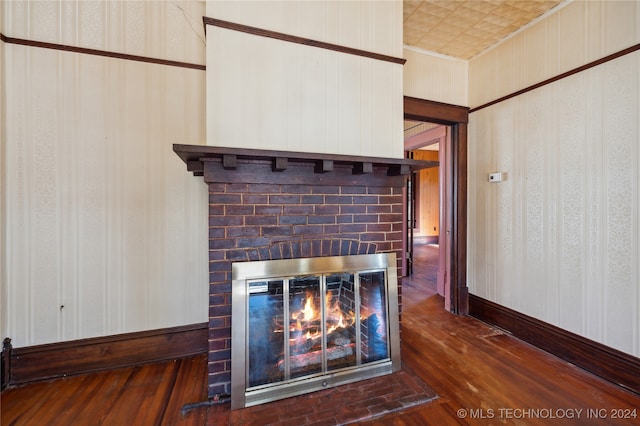 room details featuring hardwood / wood-style floors, wooden walls, and a brick fireplace