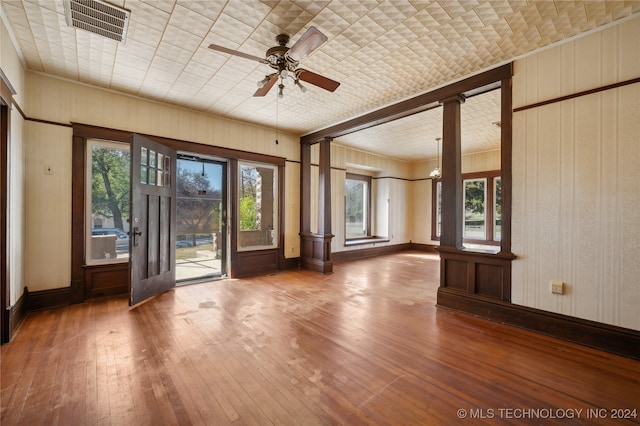 interior space featuring decorative columns, hardwood / wood-style flooring, and ceiling fan