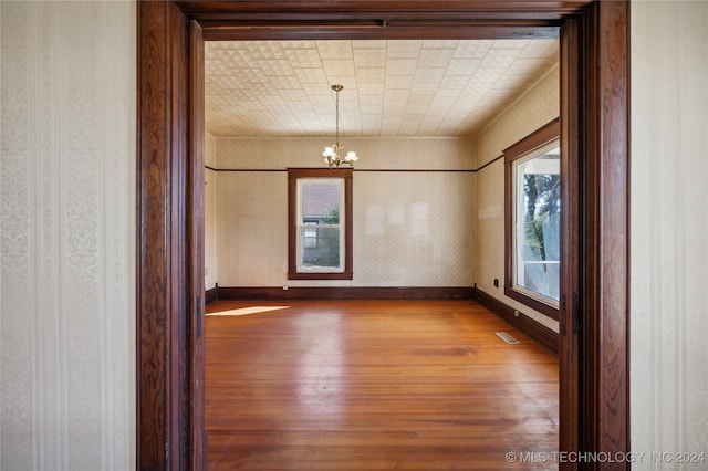 empty room featuring hardwood / wood-style flooring and an inviting chandelier