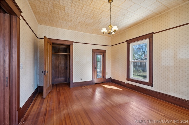 unfurnished bedroom with dark wood-type flooring and a notable chandelier