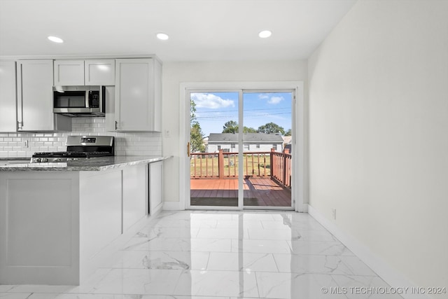 kitchen with stainless steel appliances, stone counters, and backsplash