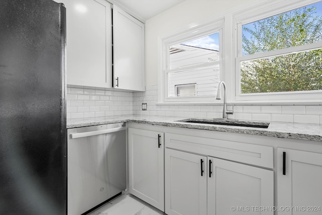 kitchen featuring dishwasher, sink, tasteful backsplash, light stone countertops, and white cabinetry