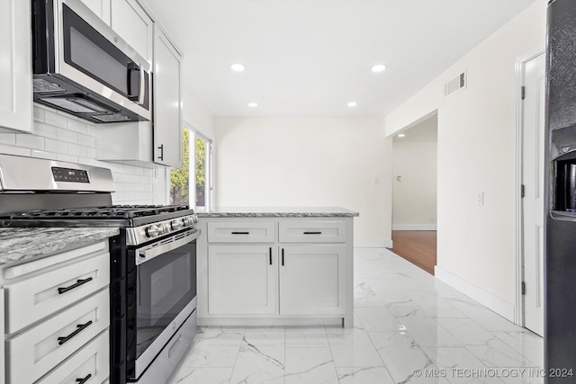 kitchen featuring tasteful backsplash, appliances with stainless steel finishes, light stone counters, and white cabinets