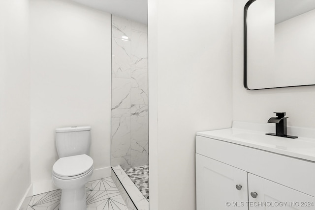 bathroom featuring tile patterned flooring, vanity, toilet, and tiled shower