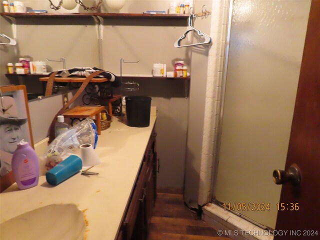 bathroom featuring hardwood / wood-style flooring, a shower with door, and vanity