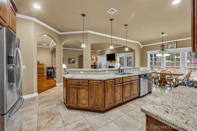 kitchen with sink, stainless steel appliances, light stone counters, an island with sink, and decorative light fixtures