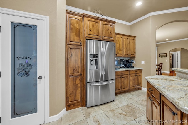 kitchen featuring brown cabinets, crown molding, stainless steel fridge with ice dispenser, and light stone countertops