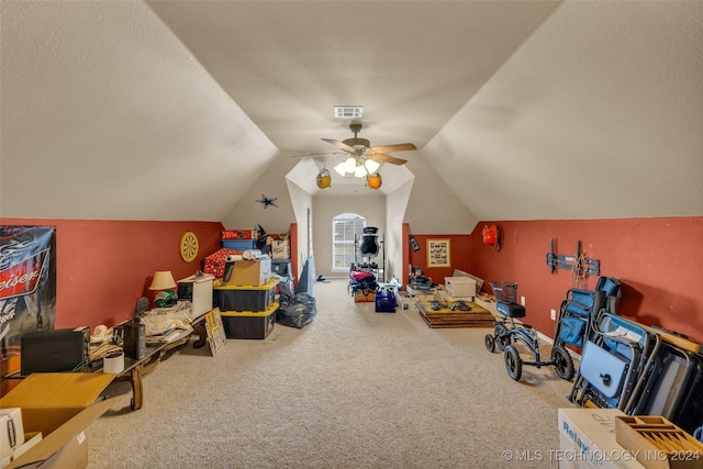 recreation room with carpet, visible vents, vaulted ceiling, a textured ceiling, and ceiling fan