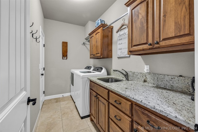 washroom with cabinet space, light tile patterned floors, baseboards, washer and dryer, and a sink