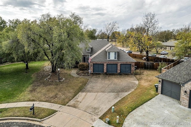 traditional-style house featuring driveway, roof with shingles, fence, and a front yard