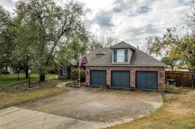 exterior space with driveway, roof with shingles, fence, a front lawn, and brick siding