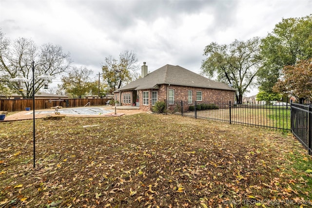 view of home's exterior with a chimney, a patio area, brick siding, and a fenced backyard