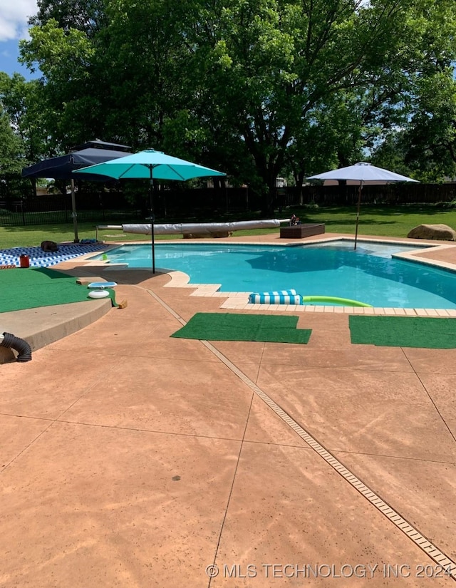 view of swimming pool with a yard, a patio, fence, and a covered pool