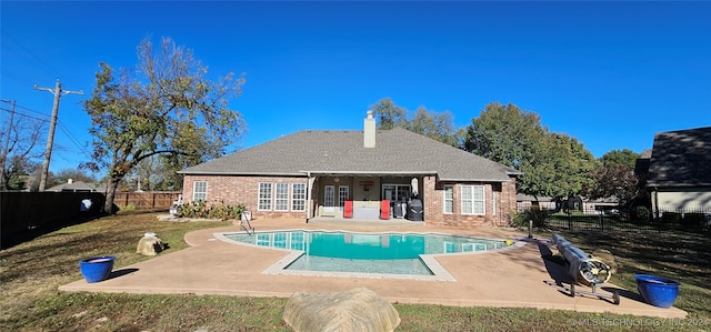 back of house with a fenced in pool, brick siding, a patio, a chimney, and a fenced backyard