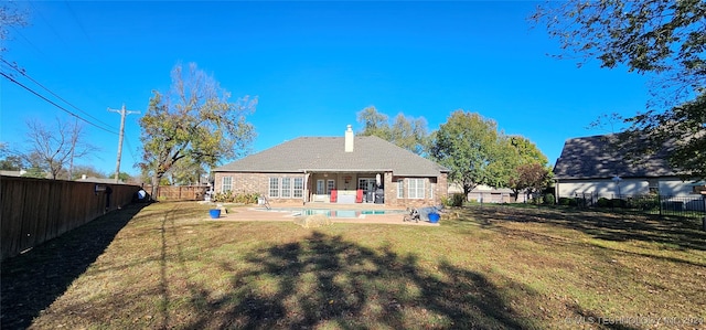 rear view of house featuring a fenced in pool, a patio, and a lawn