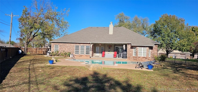 back of property with a fenced in pool, a patio, and a yard