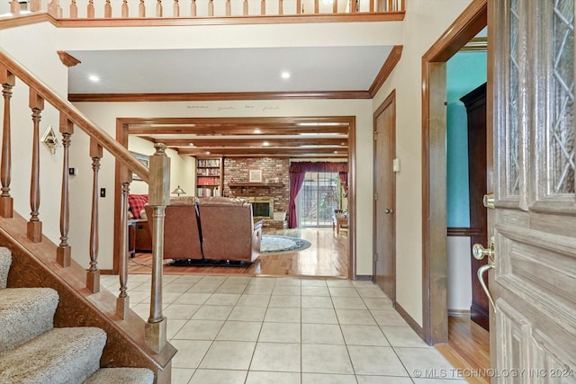 tiled foyer entrance featuring crown molding and a fireplace