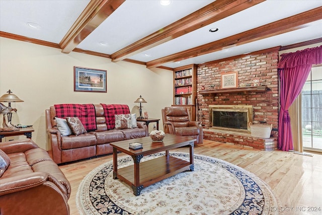 living room featuring built in features, beam ceiling, ornamental molding, a brick fireplace, and light wood-type flooring