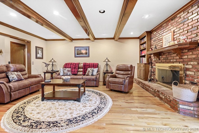 living room featuring beamed ceiling, ornamental molding, a fireplace, and light wood-type flooring