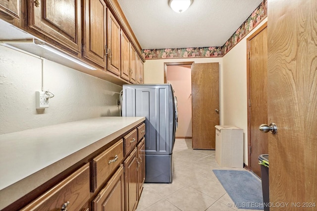 laundry room featuring cabinets, washer / clothes dryer, a textured ceiling, and light tile patterned floors