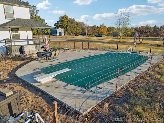 view of pool with a lawn, a storage unit, and a patio area