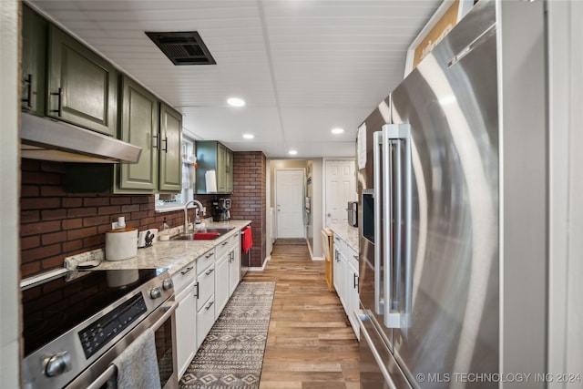 kitchen featuring white cabinetry, sink, light stone counters, appliances with stainless steel finishes, and light wood-type flooring