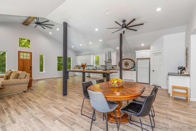 dining room with light hardwood / wood-style floors, vaulted ceiling with beams, ceiling fan, and sink