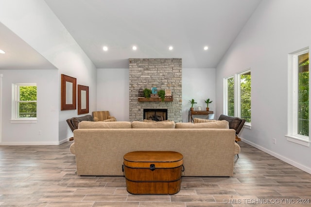 living room with high vaulted ceiling, a fireplace, and light hardwood / wood-style flooring