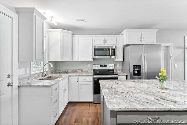 kitchen with dark hardwood / wood-style flooring, light stone counters, sink, white cabinetry, and appliances with stainless steel finishes