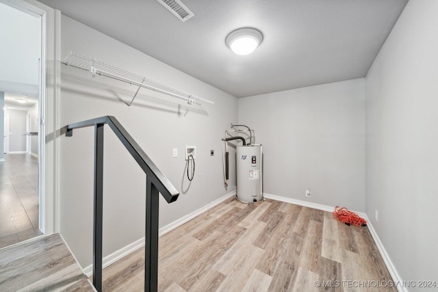 washroom featuring electric water heater, washer hookup, and light wood-type flooring