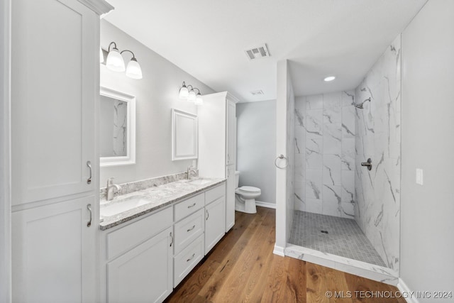 bathroom featuring toilet, vanity, hardwood / wood-style floors, and tiled shower