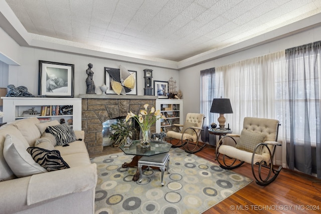 living room with a stone fireplace and hardwood / wood-style floors