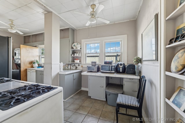 kitchen with stainless steel appliances, gray cabinets, tile countertops, and ceiling fan