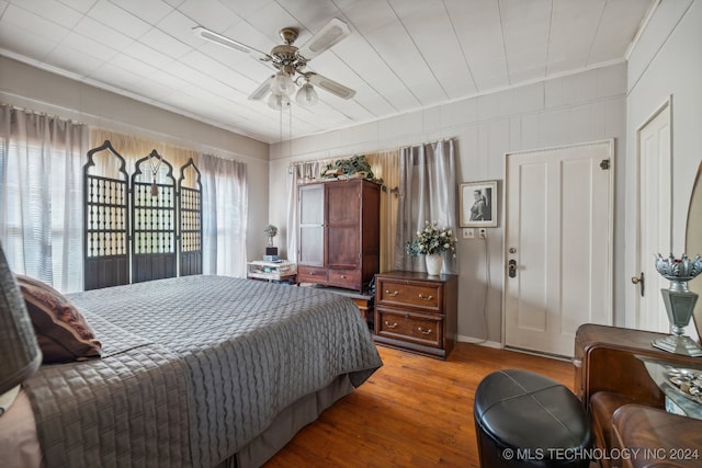 bedroom featuring hardwood / wood-style floors, ceiling fan, multiple windows, and crown molding