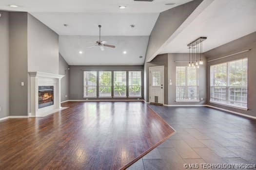 unfurnished living room with high vaulted ceiling, a wealth of natural light, hardwood / wood-style floors, and ceiling fan