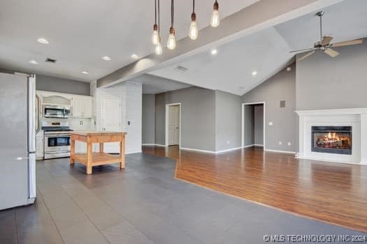 kitchen with stainless steel appliances, pendant lighting, dark hardwood / wood-style floors, white cabinetry, and lofted ceiling with beams