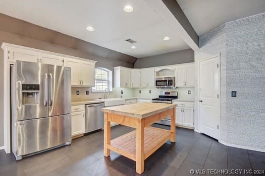 kitchen with tile walls, appliances with stainless steel finishes, and white cabinets