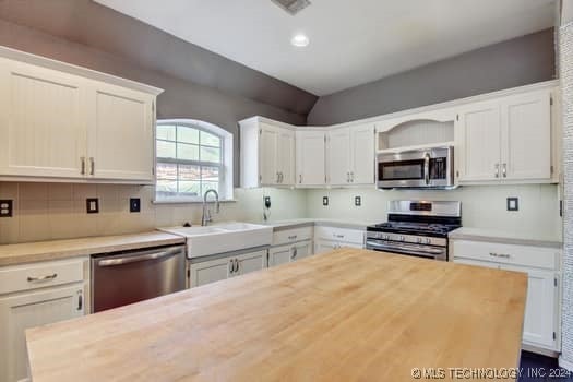 kitchen with white cabinetry, decorative backsplash, appliances with stainless steel finishes, and sink