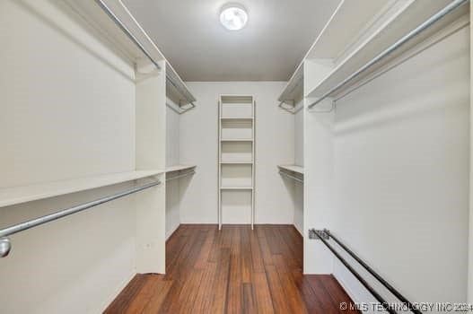 walk in closet with dark hardwood / wood-style floors