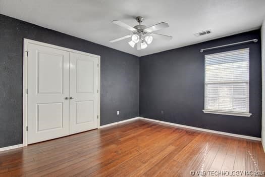 unfurnished bedroom featuring hardwood / wood-style flooring, ceiling fan, and a closet