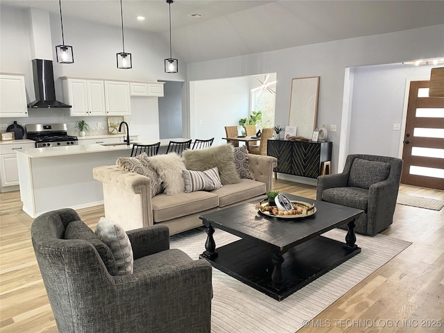 living room with light hardwood / wood-style floors, lofted ceiling, and sink