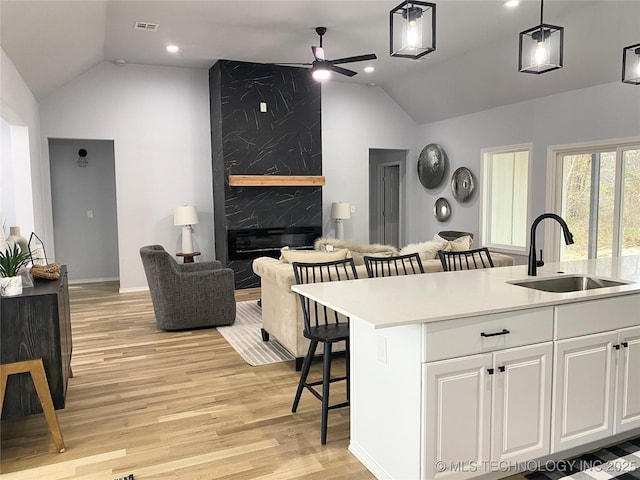 kitchen featuring ceiling fan, sink, a center island with sink, white cabinetry, and hanging light fixtures