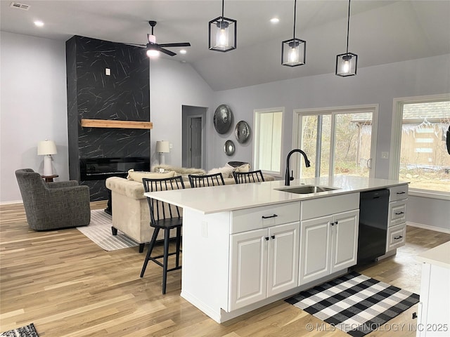 kitchen featuring white cabinets, decorative light fixtures, dishwasher, and an island with sink