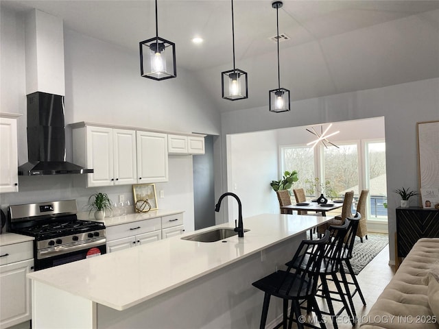 kitchen with white cabinets, stainless steel gas stove, sink, and vaulted ceiling