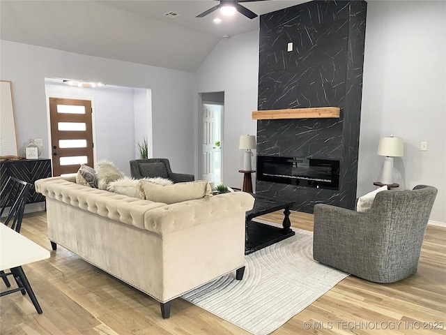 living room with a fireplace, hardwood / wood-style flooring, vaulted ceiling, and ceiling fan