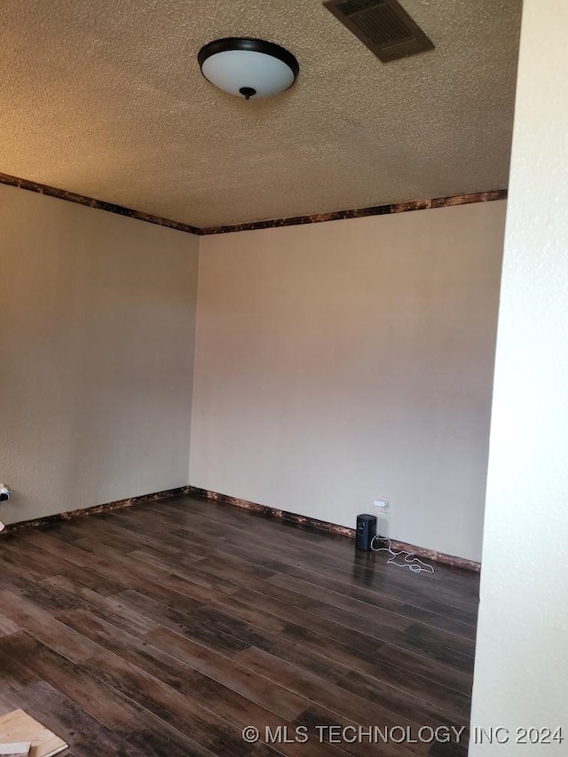 empty room with a textured ceiling and dark hardwood / wood-style floors